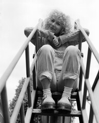 Low point of view of funny woman sitting on slide ladder.