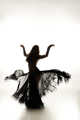 A mesmerizing woman in a black dress gracefully dances.