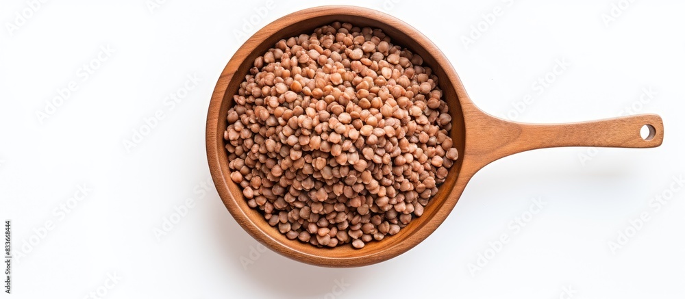 Poster a top view image of buckwheat kernels in a wooden bowl with a spoon set against a white background t