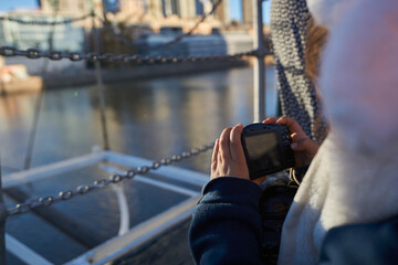 a girl taking photos of some boats in a port.