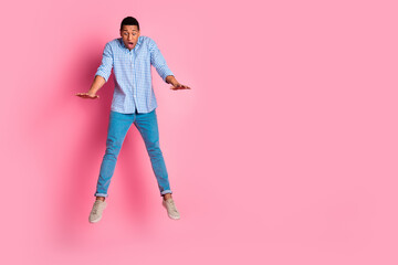 Full length photo of attractive funny guy wear plaid shirt jumping falling emtpy space isolated pink color background