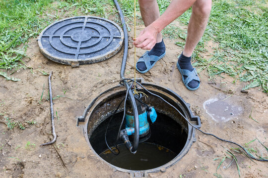 Man pumps wastewater out of the septic tank using submersible sump pump.
