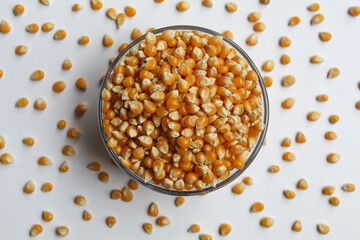 Dried corn kernels full in glass transparent bowl, isolated on white background, flat lay or top view