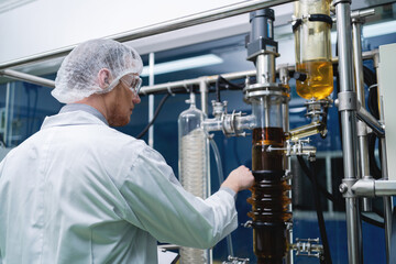 A scientist in a lab coat is working on a machine. The lab is clean and organized. The scientist is focused on his work and he is in a serious mood