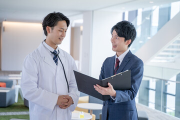 病院で笑顔で会話する男性医師と医薬情報担当者MR