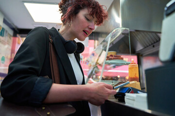 Young happy woman wears white shirt and black blazer hold pay waiter hold mobile cell phone...