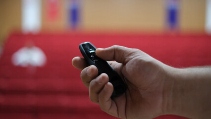 A lecture hall and a person holding a presentation remote control. Close-up