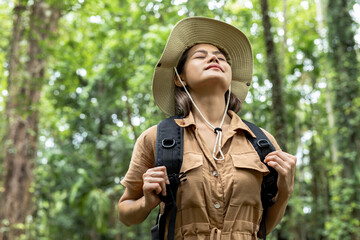 Young Asian woman makes a deep breath and enjoy the fresh air while walking in nature forest with...