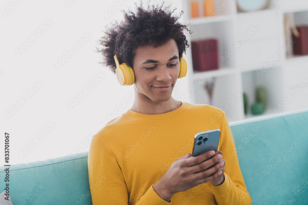 Poster Portrait of nice young man headphones use phone wear yellow pullover white interior flat indoors