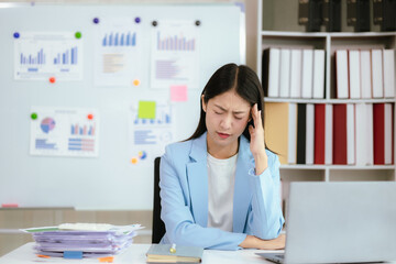 Asian businesswoman who is suffering from headache and stress due to overwork.