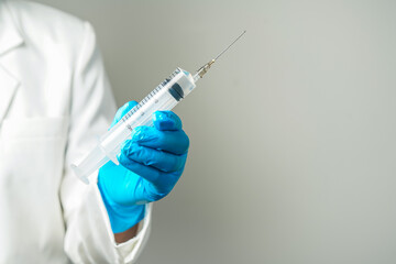 doctor or scientist holding a syringe in blue gloves