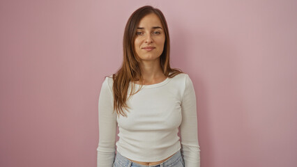 Obraz premium Attractive young caucasian blonde woman in a white sweater and denim jeans stands confidently over an isolated pink background wall.