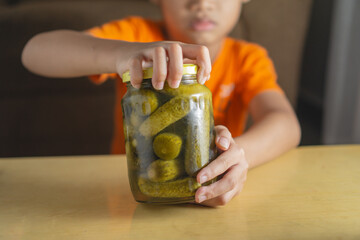 kid trying to open up tight cucumber pickle jar