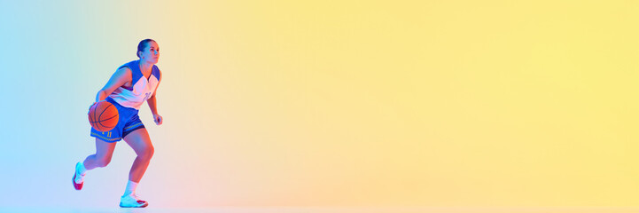 Banner. Young athletic woman in basketball gear dribbling in action in neon light against gradient studio background. Concept of professional sport, championship, tournament, hobby and recreation. Ad