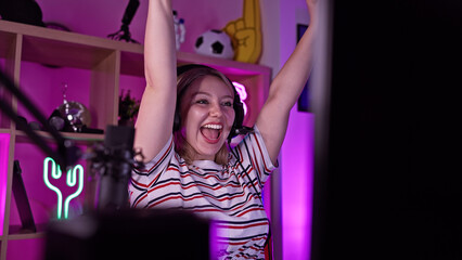 Excited woman celebrating with raised arms in a vibrant gaming room at night