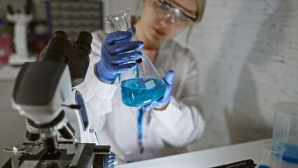 Fototapeta premium A young woman scientist examines a chemical in a flask in a laboratory setting.