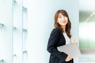 ノートパソコンを持つ笑顔の日本人ビジネスウーマン
