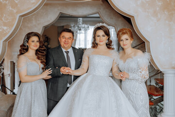 A man and three women are posing for a picture in front of a building. The man is wearing a suit...