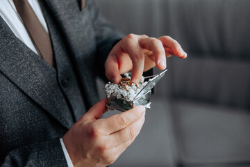 A man is holding a small box with a ring inside. He is wearing a suit and tie