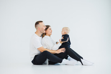 Young happy family couple with baby son on white background. Mom and dad with a baby on a white background.