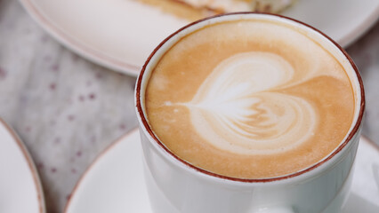 Creamy coffee in a white cup on a cafe table, perfect for a peaceful breakfast