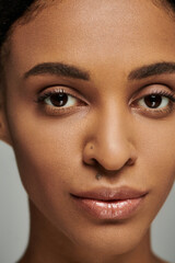 Close up of a young African American woman with striking brown eyes, focused on her skincare...