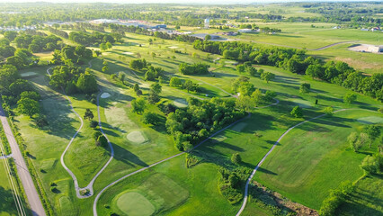 Country golf course with small town warehouses storage and water tower in distant background, municipal golf course country club in Mountain Grove, Missouri, scenic aerial view 18 holes golf