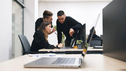 Group of businesspeople, mates involved in teamwork use laptop, look at device screen, consider new business program, corporate software, look interested, engaged in collaborative project discussion