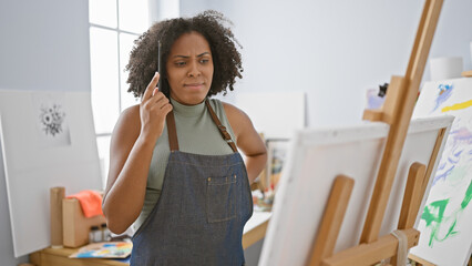 African american woman artist painting in a studio while on the phone