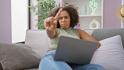 African american woman with braids gesturing no in her living room with a laptop