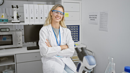 Confident woman scientist standing with arms crossed in a modern laboratory indoor setting.