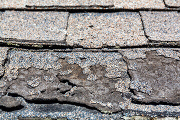 Close view of a row of weathered shingles damaged from the sun.
