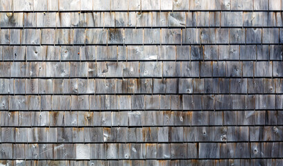 Several rows of weathered gray cedar shingles in morning light wide view.