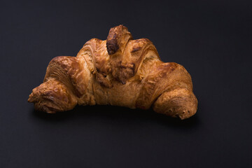 Fresh croissant on a black slate background.