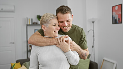 A smiling woman embraces a man in a cozy living room, conveying a warm family moment indoors.