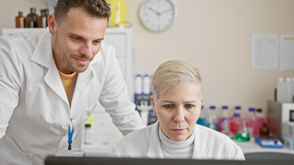 A man and woman in lab coats working together in a laboratory setting, focusing intently on scientific research.