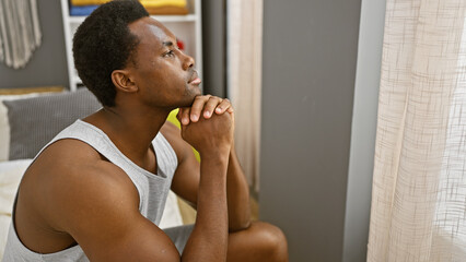 Pensive african man in bedroom looking out window, sunlight, indoor scene, contemplative, peaceful,...