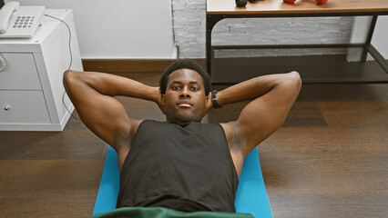 African american man exercising indoors on a blue mat in a modern home environment.
