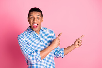 Photo of excited good mood guy wear plaid shirt showing two fingers emtpy space isolated pink color background