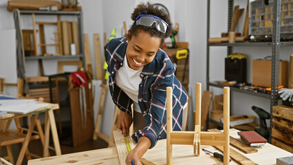 Smiling woman measuring wood in a carpentry workshop, embodying craftsmanship and diy spirit.