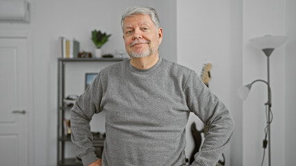Mature grey-haired man standing confidently in a modern living room, exuding a friendly demeanor