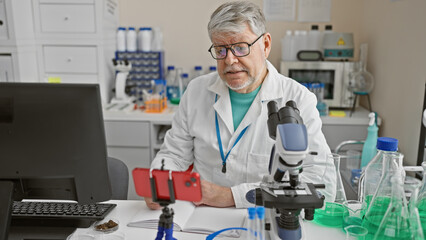 Middle-aged man conducting a video call in a laboratory setting with scientific equipment around...
