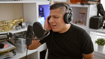 Striking portrait, serious young latin man, a professional musician, totally engrossed singing his song, unleashing his handsome voice in a music studio during a leisurely filled performance