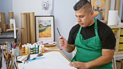 Handsome young latin artist, seriously immersed in his hobby, joyfully drawing his personal journey...