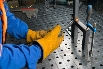 a master in protective gloves and clothing fastens metal parts with gas welding