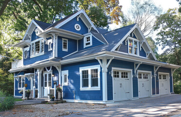 Blue and white two story house with a large front yard, black driveway