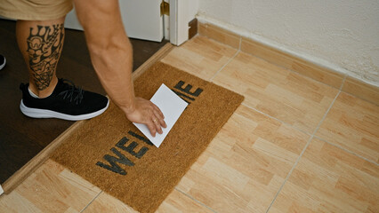 Man receiving envelope indoors portrayed near welcome mat, signaling personal or business correspondence at home.