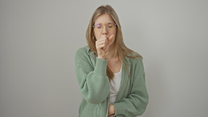 A blonde woman in casual wear coughing into her hand against a white background
