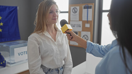 Two women engage in an interview at a european electoral polling station, with a microphone and the...
