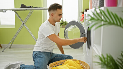 A young man is loading laundry into a washing machine in a bright home interior.